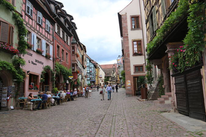 Menschen laufen durch die Altstadt von Riquewihr.